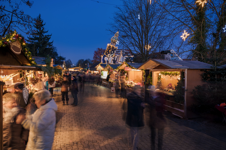 Weihnachtsmarkt bei Nacht mit beleuchteten Ständen und Kuchlbauer Turm im Hintergrund