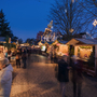 Weihnachtsmarkt bei Nacht mit beleuchteten Ständen und Kuchlbauer Turm im Hintergrund